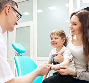 Mother holding baby and talking to pediatric dentist