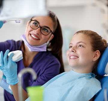 Dental team member and young patient looking at chairside computer screen