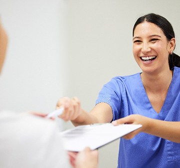 Orthodontic assistant smiling while handing patient forms