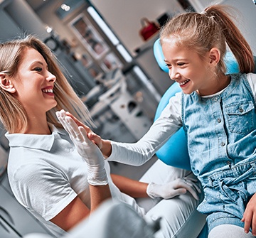 Young patient high fiving team member during children's dentistry checkup and teeth cleaning