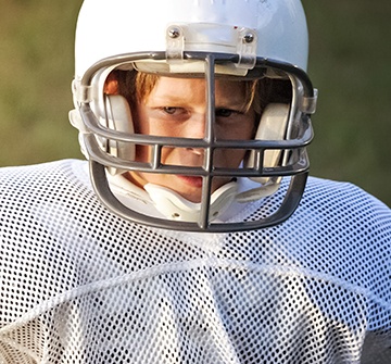 Child in football equipment and athletic mouthguard