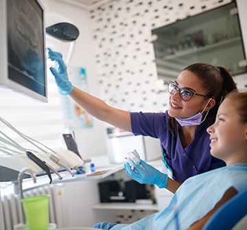 Dental team member and child looking at digital x-rays