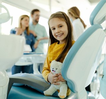 Child smiling while pediatric dentist in Clinton talks to parents