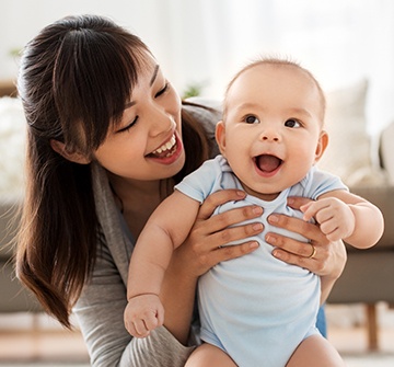 Mother holding laughing baby after fluoride treatment