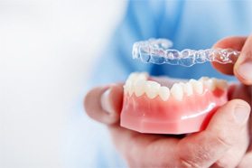 Clinton orthodontist placing aligner over model of teeth