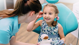 Dental team member talking to child in dental chair