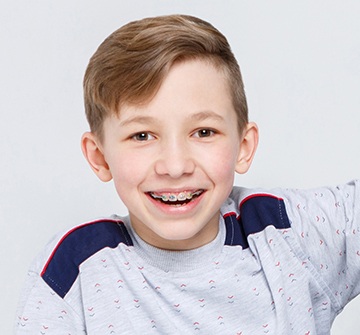 Preteen child with traditional orthodontics smiling