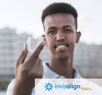 Young man holding up an Invisalign Teen aligner tray