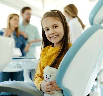 Child smiling while dentist discusses dental sealants in Clinton with parents