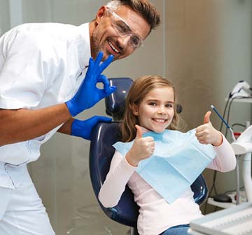 Child giving thumbs up with pediatric dentist in Clinton