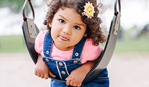 Little girl playing on playground after dentistry for toddlers visit