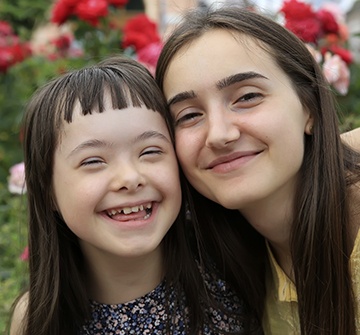 Two young women smiling together after special needs dentistry