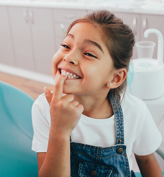 Young girl pointing to her teeth during pediatric dental office visit