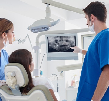 Dentist dental team member and patient looking at digital x-rays