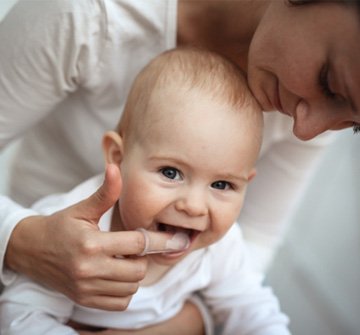 Closeup of mother showing how to help teething baby in Clinton