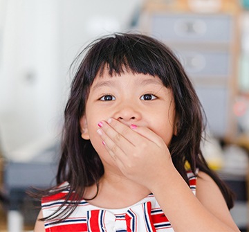 Child in need of emergency kids dentistry covering mouth