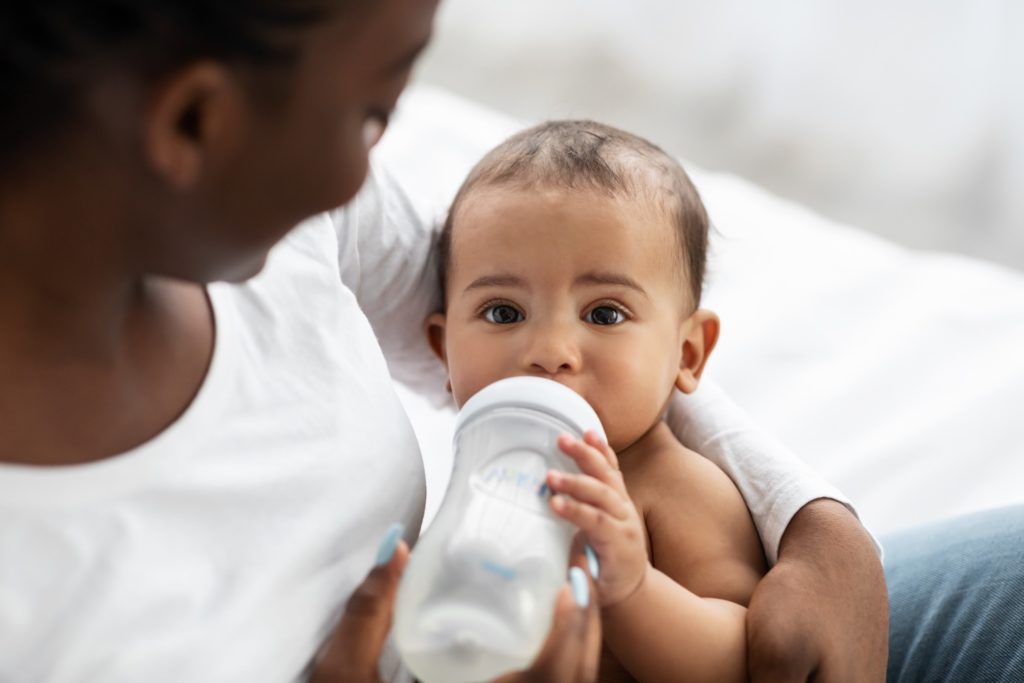 Mother holding baby while they drink a bottle of milk